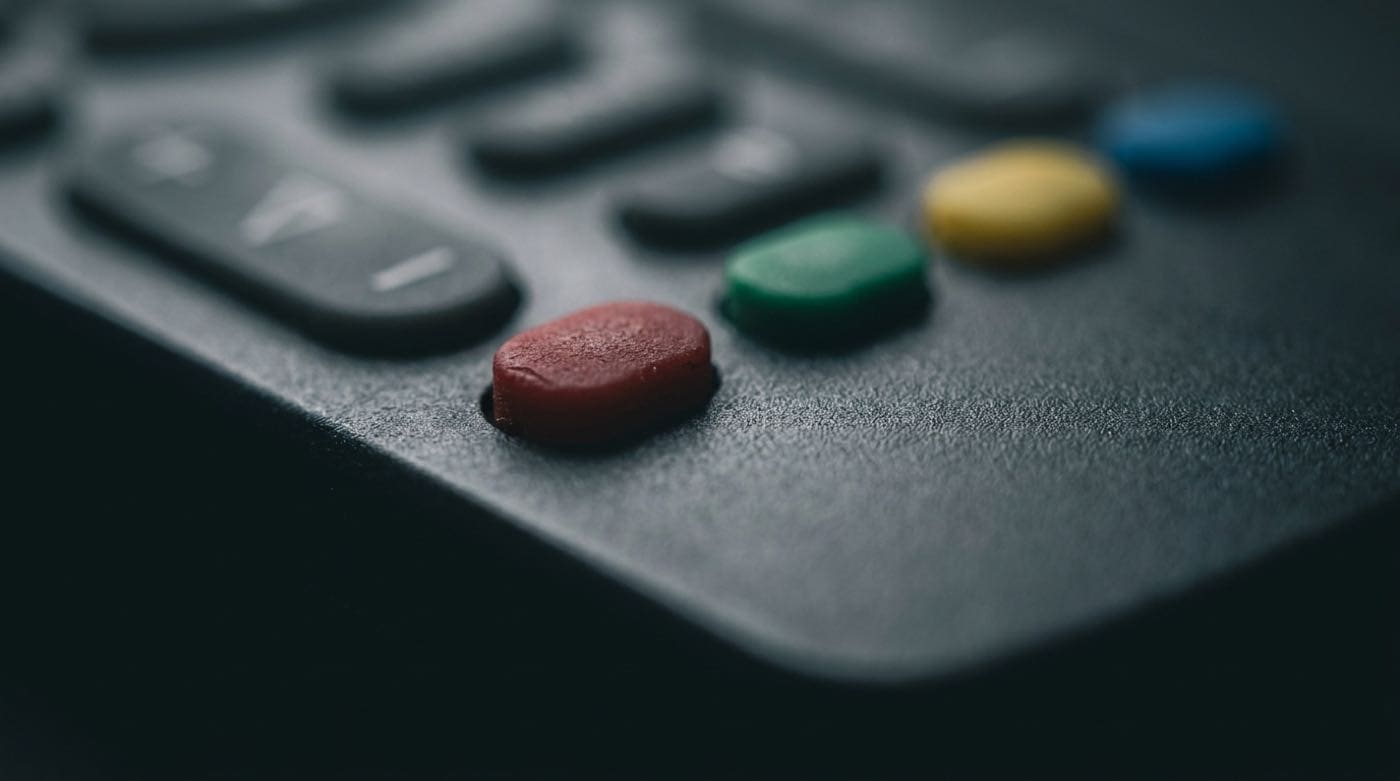 Macro of the four coloured function keys on a television remote, the red key in focus